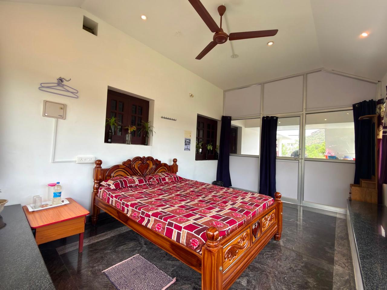 Comfortable room with wooden bed at Amaravathy Rooms and Homestay